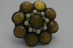 broche cabochons moutarde , perles beige clair , sur fond de capsule noire. diamètre de la capsule : 3.5cm